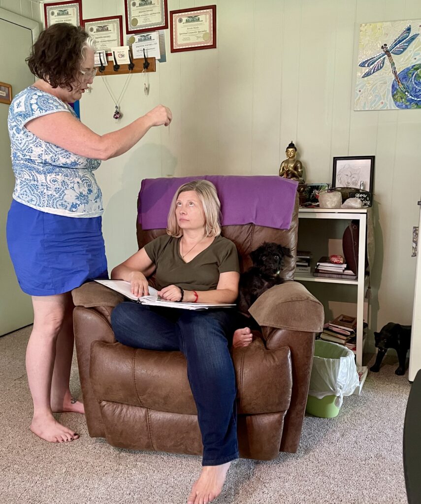 Hypnosis certification student Debby practices an eye-fatigue hypnosis induction with Tara during hands-on training, demonstrating a traditional focused-attention technique under professional instruction.
